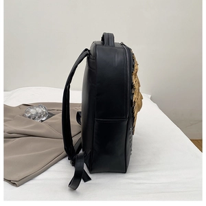 Side view of black leather backpack featuring a golden lion head and metallic studs