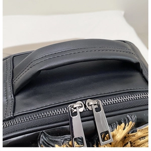 Top detail of black leather backpack with reinforced handle and gold eagle emblem