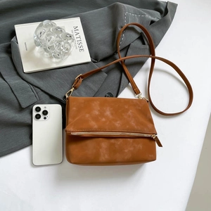 Vintage brown leather saddle bag with gold zipper detail on a minimalist desk setup