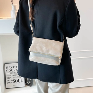 Minimalist beige vintage saddle bag with gold zipper detail shown in a lifestyle setting