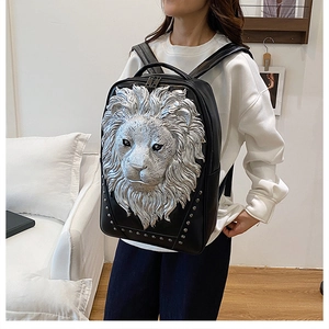 Detail of 3D silver lion head relief and metal studs on black leather backpack