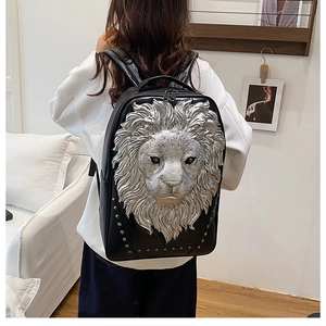 Detail of black leather backpack featuring 3D silver lion head relief and metal rivets