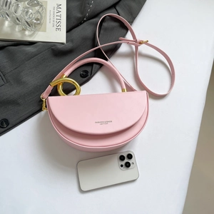 Pink leather half-moon shoulder bag with gold ring hardware and adjustable strap
