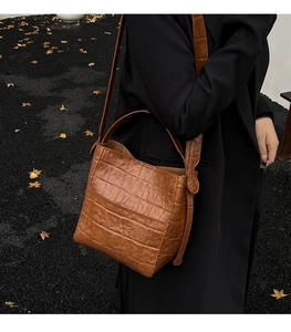 Detailed view of a brown stone-patterned bucket bag styled with a black autumn coat
