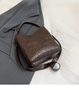 Detail of dark brown faux crocodile bucket bag showing texture and adjustable strap