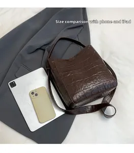 Size comparison of dark brown crocodile pattern bucket bag with phone and tablet