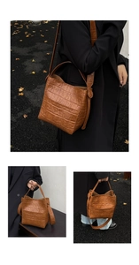 Detail view of brown crocodile texture bucket bag with handles and long shoulder strap