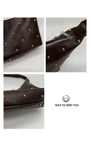 Detailed views of silver studs and smooth zipper on a dark brown leather shoulder bag