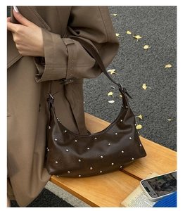 Detailed shot of dark brown leather hobo bag with silver studs and adjustable strap