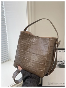 Close-up of the dark brown croc-embossed texture and sturdy handle on this bucket bag