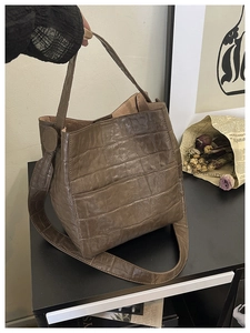 Detail of retro brown bucket bag featuring crocodile pattern texture and metal buckle