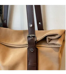 Detail of camel suede tote bag showing brown leather strap and silver metal buckle