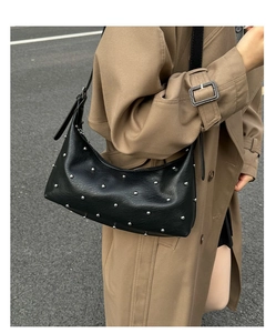Close-up of black leather hobo bag featuring silver rivets and adjustable shoulder strap