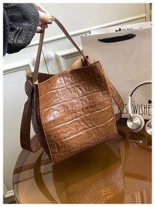 Close-up of the vintage brown crocodile texture on a stylish leather bucket handbag