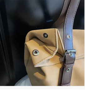 Detail of khaki tote bag featuring adjustable strap buckle and silver metal snap button