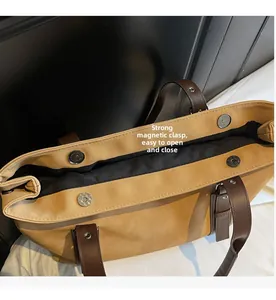 Detail view of strong magnetic buckles and black lining on a large yellow tote bag