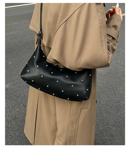 Detail of vintage black leather tote featuring silver rivet studs and a textured finish