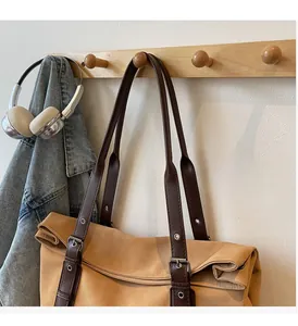 Detail of reinforced brown leather straps on a large ginger canvas tote bag