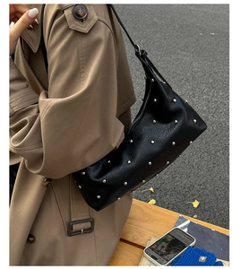 Close-up of black rivet shoulder bag on a model in a stylish urban setting