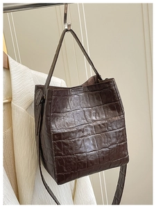Detail of dark brown croco-embossed texture on a premium bucket bag with shoulder strap