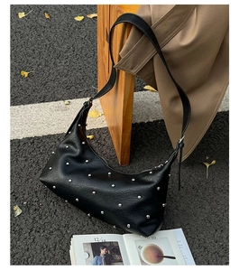 Detail of black studded hobo bag with silver rivets on textured PU leather material