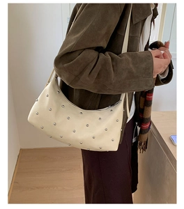 Detail of cream soft leather hobo bag with silver rivet accents and zipper closure