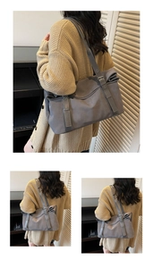 Detail of grey tote bag with adjustable shoulder strap and decorative side pleats