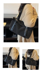 Detail of minimalist black large tote bag featuring leather straps and silver buckles