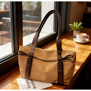 Detail of camel tote bag with brown straps and buckle decoration in warm sunlight
