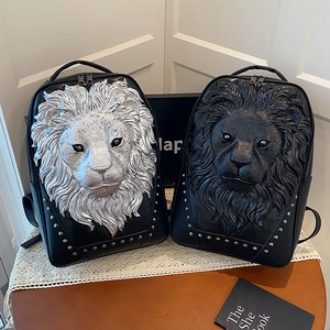 Black and silver 3D lion head backpack with metal studs on a vintage wooden table