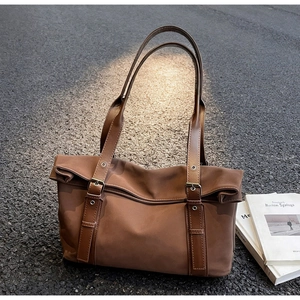 Close-up of brown leather tote bag with adjustable straps on urban asphalt street