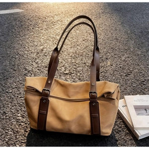 Detail of khaki tote bag with dark brown adjustable leather straps and silver buckle
