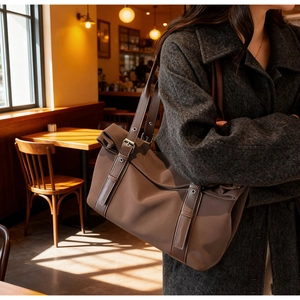 Detail of a brown tote bag with adjustable silver buckles and metal eyelet shoulder straps