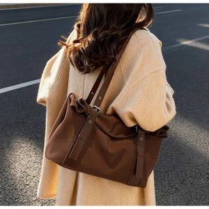 Detail of coffee tote bag with leather trim and buckle on casual wool coat