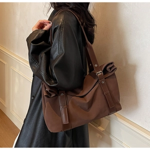 Detail of a large dark brown commute tote bag with leather straps on a model's shoulder