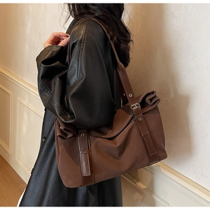 Detail of coffee brown canvas tote bag with leather straps and vintage metal buckles