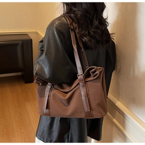 Detail of large brown tote bag showing shoulder strap and fabric texture on a model