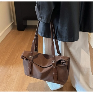 Detail view of brown vintage tote bag with metal buckles and matte synthetic leather