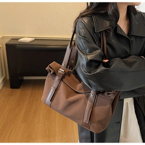 Detail of a dark brown tote bag with metal eyelet straps and vintage buckle design
