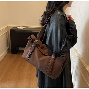 Detail of dark brown tote bag featuring nylon material and leather strap with metal grommet
