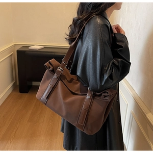 Detail of adjustable leather strap and side pocket on large brown nylon tote bag