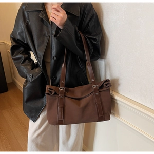 Detail of dark brown tote bag with leather straps and silver buckle for daily commute