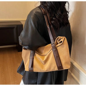 Detail of suede shoulder tote bag with decorative metal buckle and leather straps