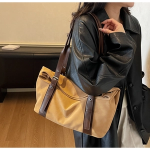 Detail of light brown tote bag with leather shoulder strap and metallic buckle adjustment