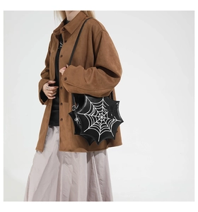 Detailed view of gothic spider web crossbody bag with spider motif on model