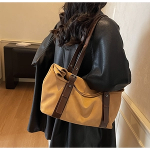 Detail view of khaki tote bag with dark brown straps and silver metal eyelets