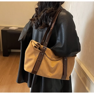 Detail of mustard yellow suede tote bag with dark brown leather straps and silver buckle