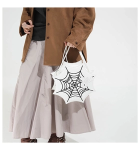 Detailed embroidery of a black spider web and spider on a unique white geometric handbag