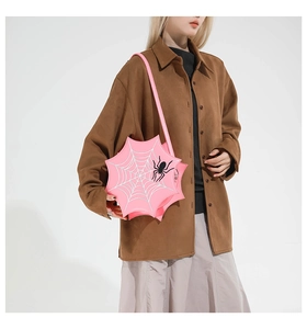 Detail of pink spiderweb shoulder bag with black spider patch on a fashion model