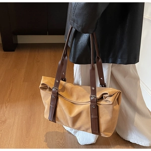 Detailed view of the buckle on the adjustable strap of a large khaki tote bag